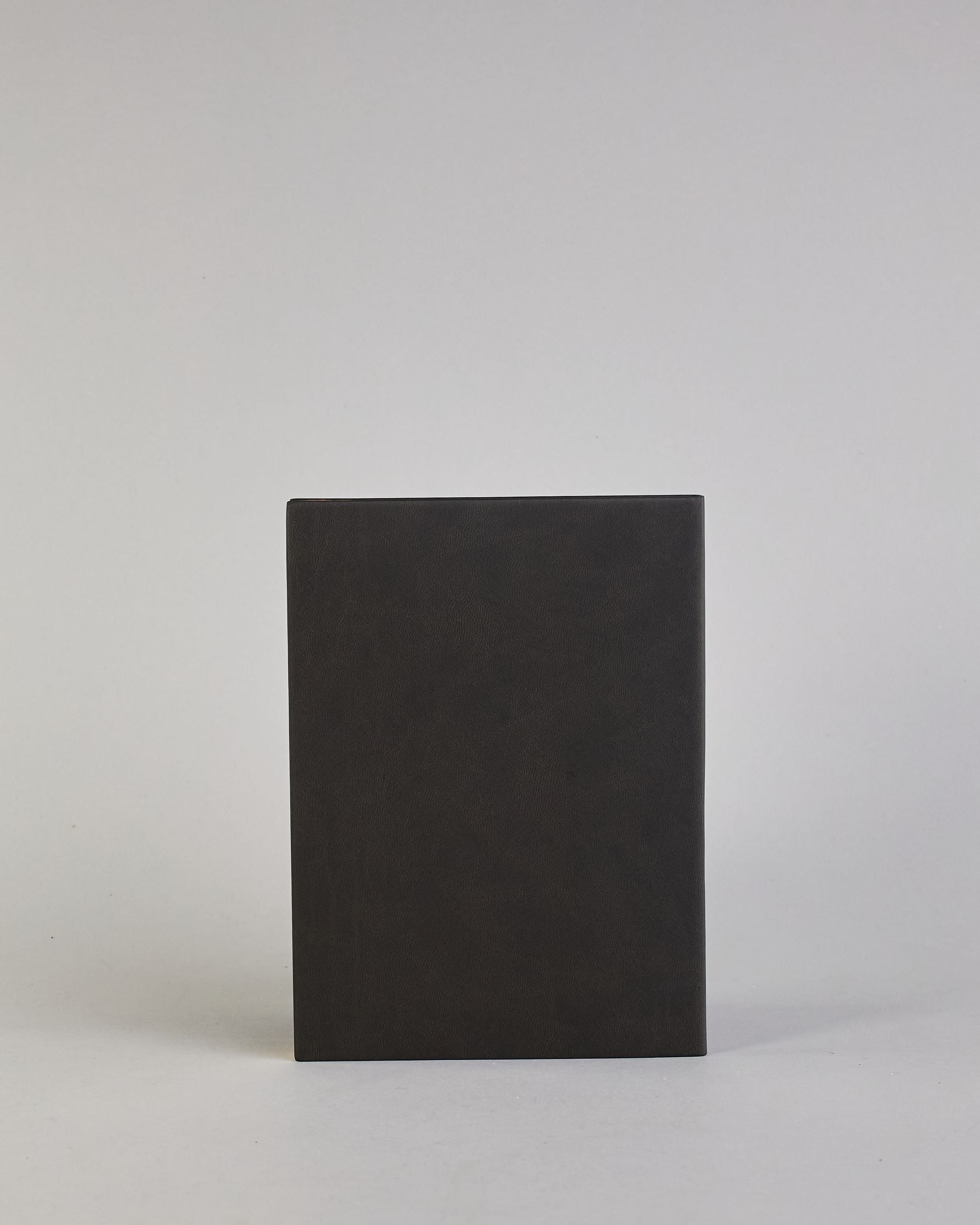 Schwarzes PU-Notizbuch mit zwei Laschen an der Vorderseite, eine Stiftschlaufe und einem zusätzlichem Fach, in dem auch ein Smartphone Platz findet. Unten dezent goldene Prägung mit dem Schriftzug ‚Somewhere‘. Ein goldfarbener Stift steckt seitlich in der Lasche. #3