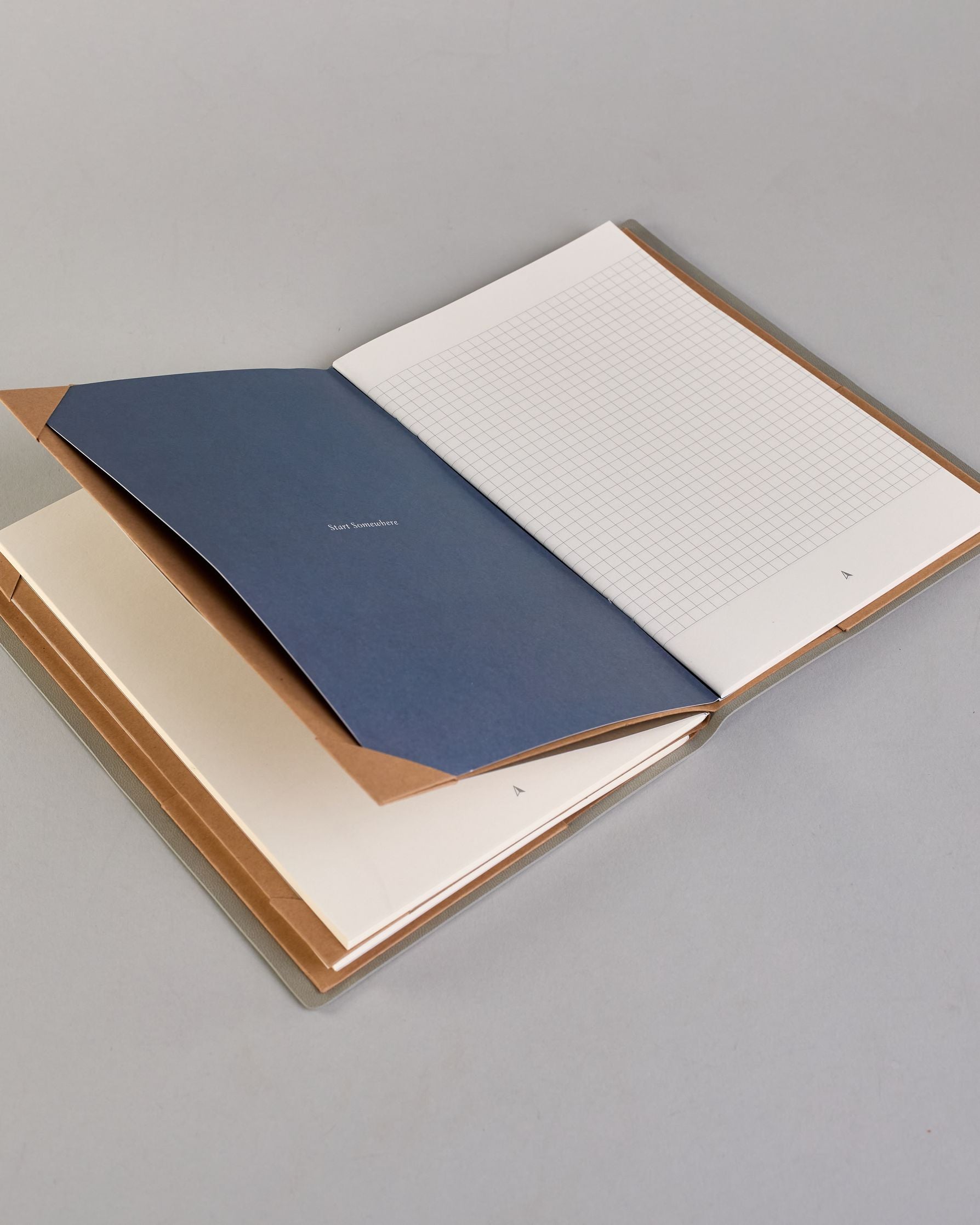 Hellgraues PU-Notizbuch mit zarter goldener Aufschrift "Going Places" auf der Vorderseite. Innen ist das System aus Kraftpapier und es können drei Hefte und ein Block flexibel eingehängt und immer wieder ausgetauscht werden. #5