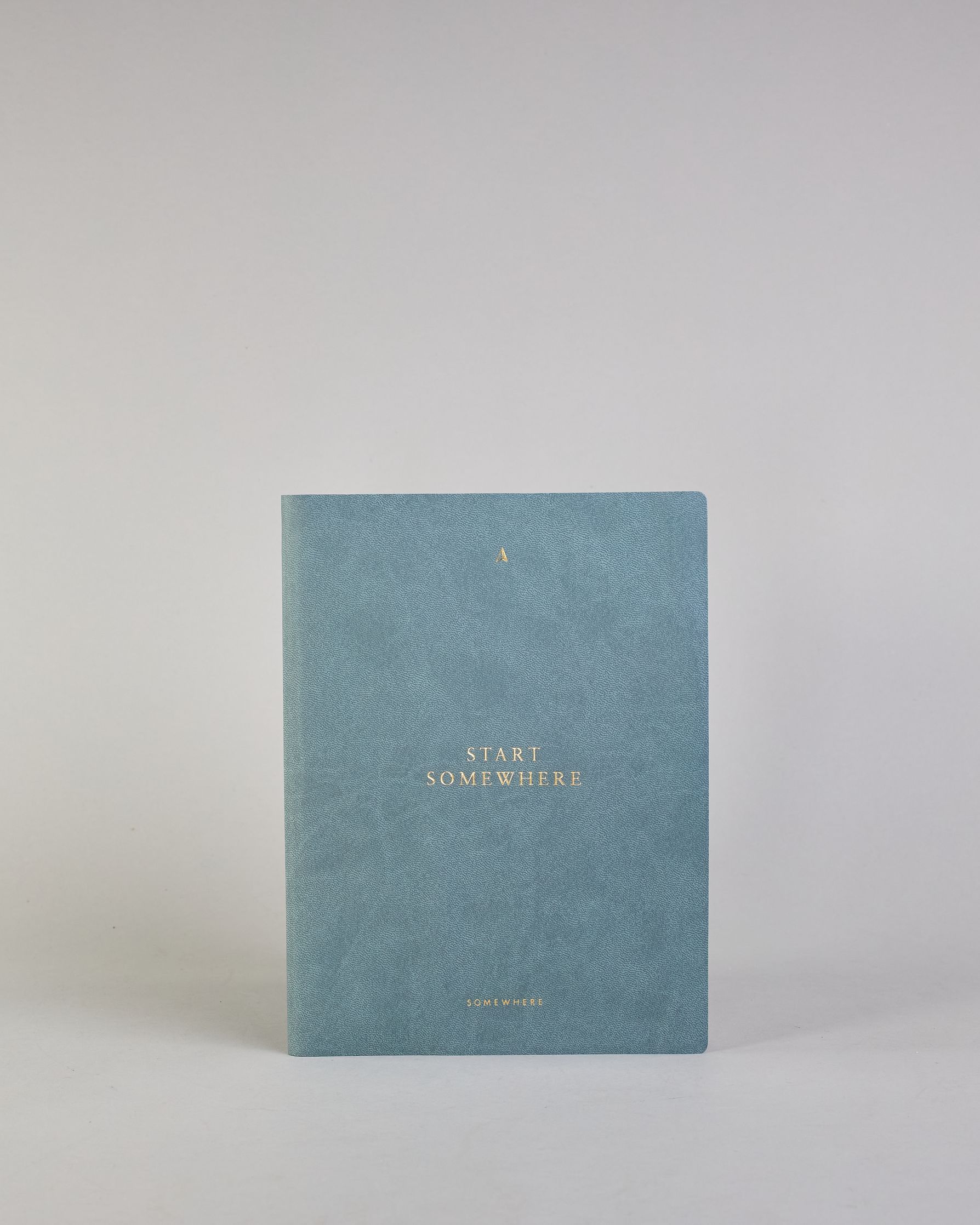 Jeansblaues PU-Notizbuch mit zarter goldener Aufschrift "Start Somewhere" auf der Vorderseite. Innen ist das System aus Kraftpapier und es können drei Hefte und ein Block flexibel eingehängt und immer wieder ausgetauscht werden. #1