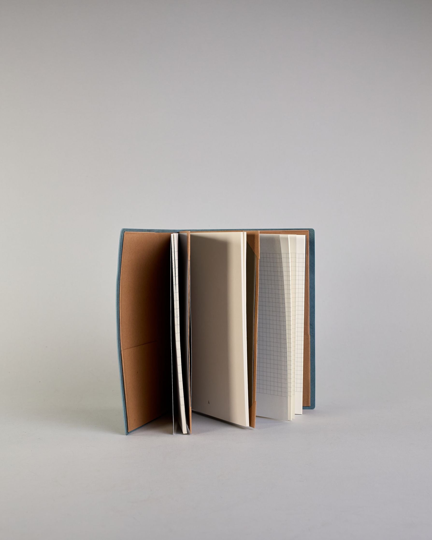 Jeansblaues PU-Notizbuch mit zarter goldener Aufschrift "Start Somewhere" auf der Vorderseite. Innen ist das System aus Kraftpapier und es können drei Hefte und ein Block flexibel eingehängt und immer wieder ausgetauscht werden. #5