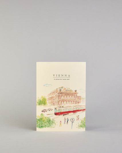 Notizbuch mit cremefarbenem Einband, darauf eine zarte Illustration der Wiener Staatsoper mit vorbeifahrender Straßenbahn und kleinen Figuren im Vordergrund. Titel: ‚Vienna – le journal de l’après-midi. Innen ist jede Seite individuell illustriert. #1