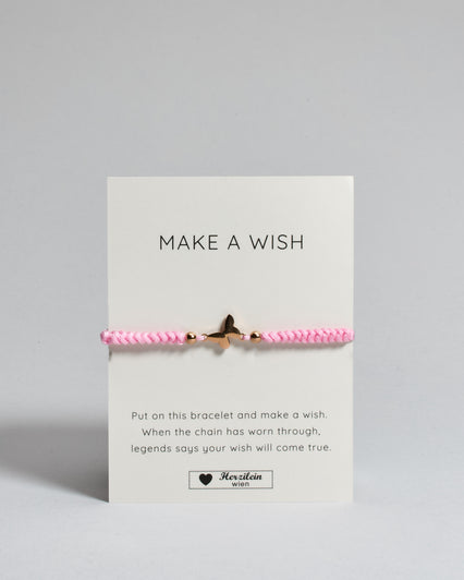 Rosa Armband mit rosé Schmetterlingsanhänger. Kommt auf einer Karte auf der oben "Make a wish" und unten "Put on this bracelet and make a wish. When the chain has worn through, legends say your wish will come true". 