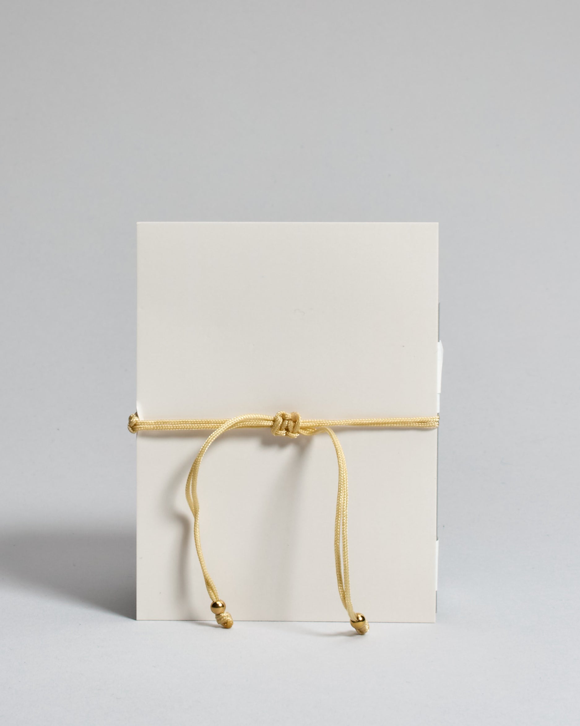 Goldenes Armband mit goldenem Sonnenanhänger. Kommt auf einer Karte auf der oben "Make a wish" und unten "Put on this bracelet and make a wish. When the chain has worn through, legends say your wish will come true". 