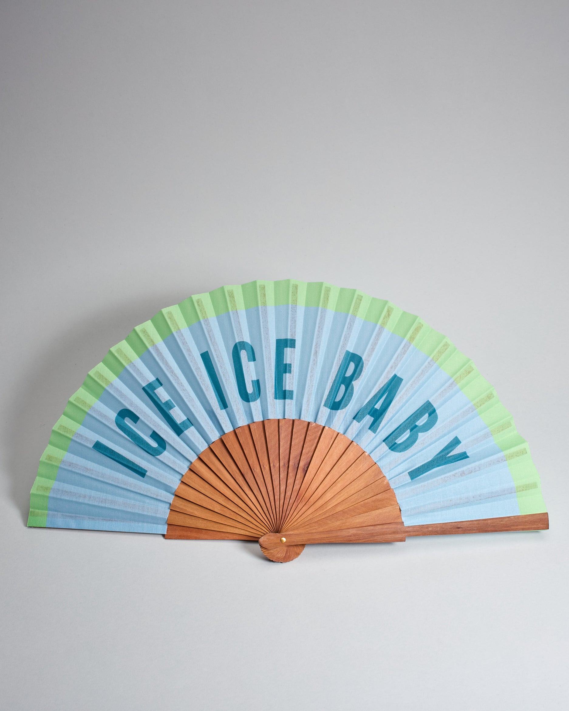 Fächer aus geöltem Holz mit Stoffbezug der oben einen grünen Rand hat und sonst hellblau ist. Es steht große "Ice Ice Baby" drauf. 