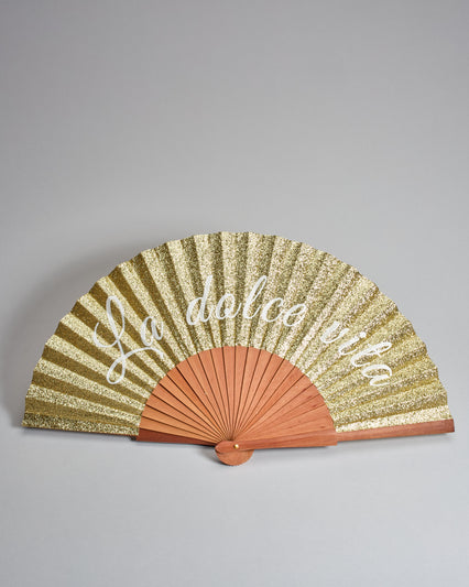 Fächer aus geöltem Holz mit Glitzer-Bespannung in gold. Es steht groß "La dolce vita" drauf. 