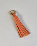 Schlüsselanhänger in Quastenform aus echtem Rindsleder. Das Leder ist orange, der Ring mit dem man das Lederaccessoire an Schlüssel oder Tasche befestigen kann ist gold.