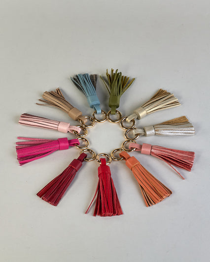 Schlüsselanhänger in Quastenform aus echtem Rindsleder. Das Leder ist orange, der Ring mit dem man das Lederaccessoire an Schlüssel oder Tasche befestigen kann ist gold.