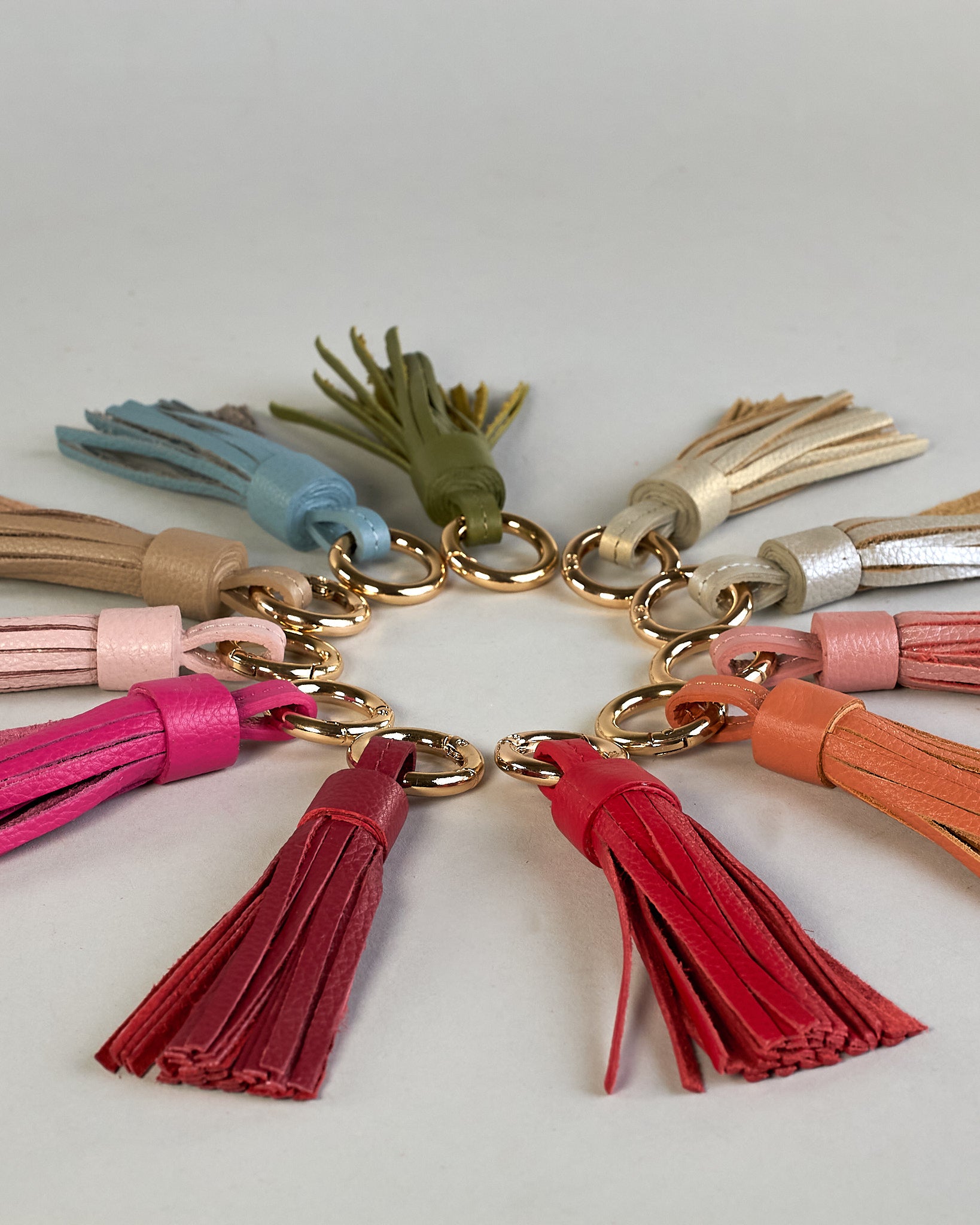 Schlüsselanhänger in Quastenform aus echtem Rindsleder. Das Leder ist orange, der Ring mit dem man das Lederaccessoire an Schlüssel oder Tasche befestigen kann ist gold.