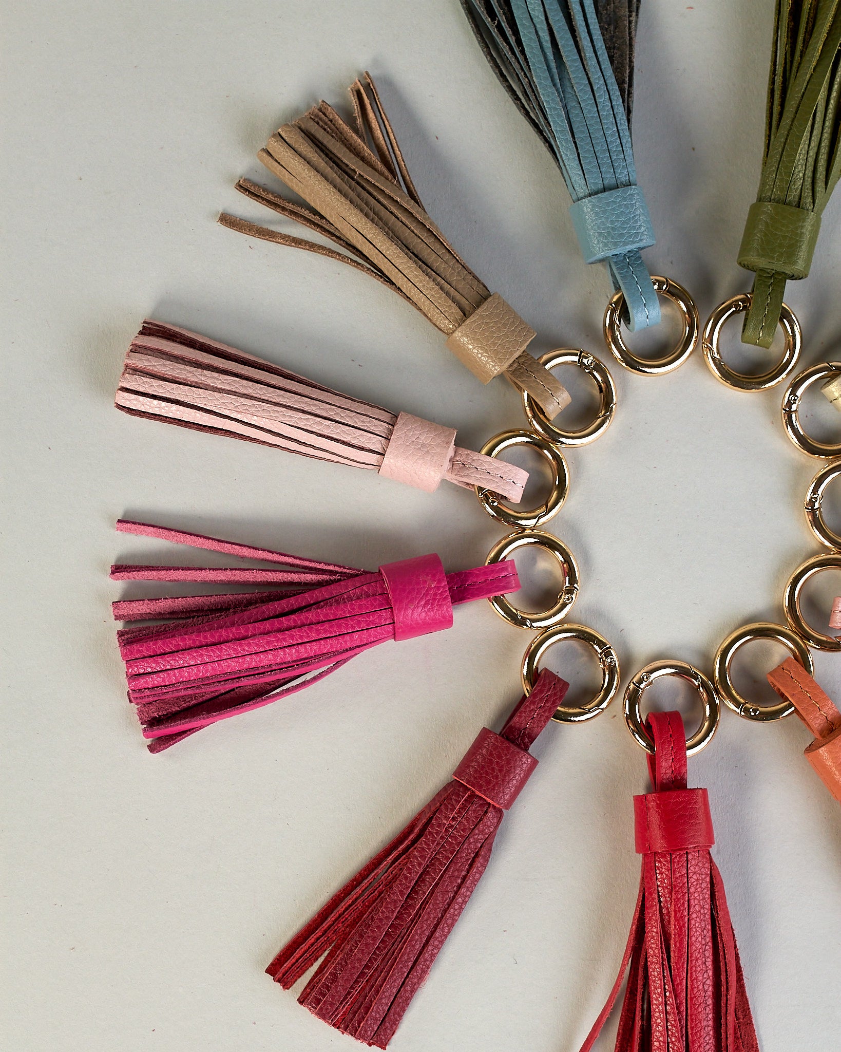 Schlüsselanhänger in Quastenform aus echtem Rindsleder. Das Leder ist orange, der Ring mit dem man das Lederaccessoire an Schlüssel oder Tasche befestigen kann ist gold.