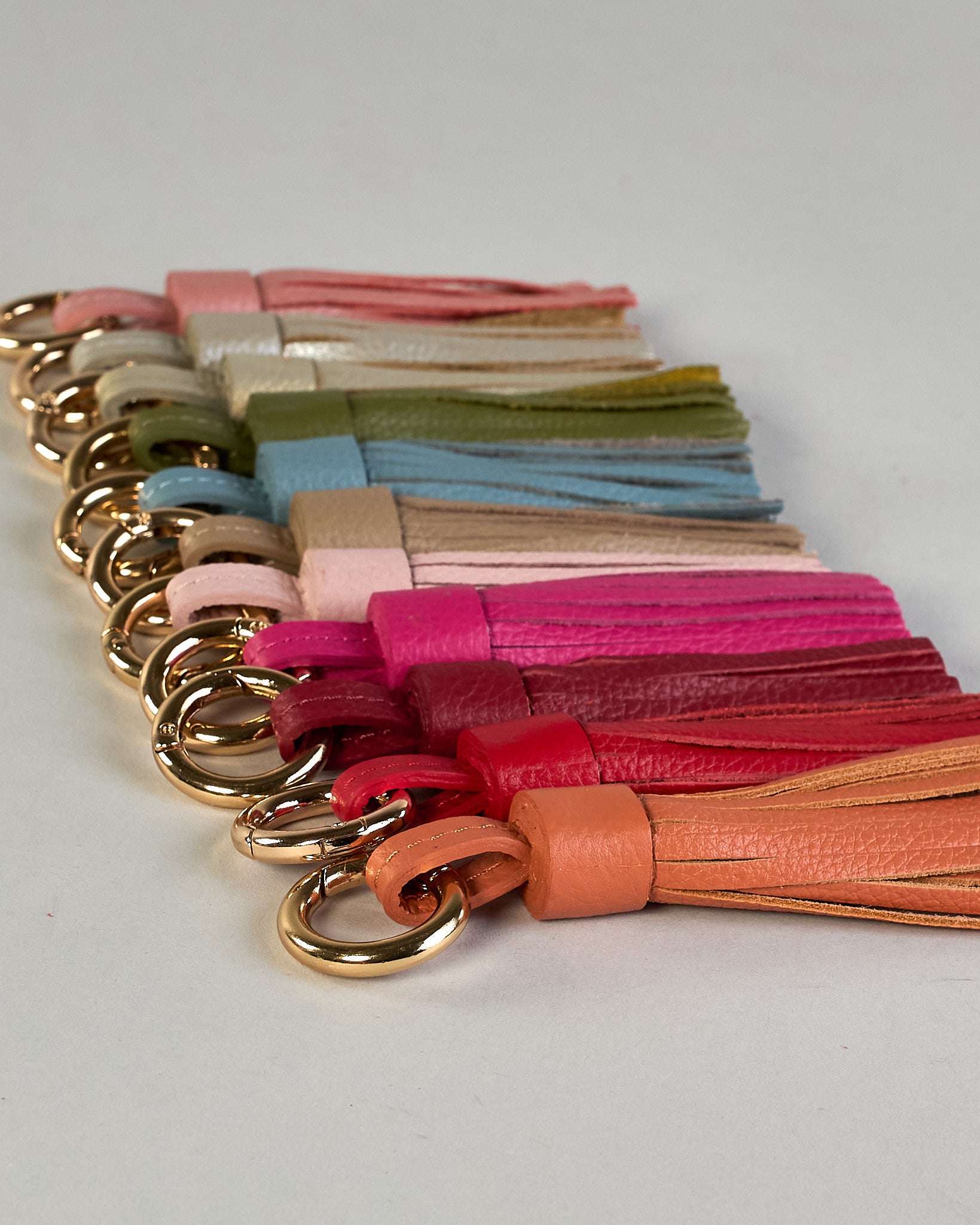 Schlüsselanhänger in Quastenform aus echtem Rindsleder. Das Leder ist orange, der Ring mit dem man das Lederaccessoire an Schlüssel oder Tasche befestigen kann ist gold.