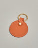 Schlüsselanhänger in Kreisform aus echtem Rindsleder. Das Leder ist orange, der Ring mit dem man das Lederaccessoire an dem Schlüssel befestigen kann ist gold. Auf der Rückseite ist die das Logo "Herzilein Wien" eingeprägt. Die Vorderseite kann personalisiert werden.
