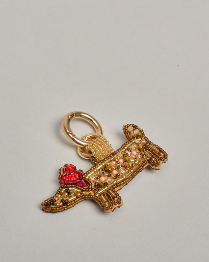 Schlüsselanhänger mit handgemachter Perlenstickerei in Form eines Dackels mit einem roten kleinen Barett am Kopf. Die Perlenfarben sind beige, braun und rot. #1