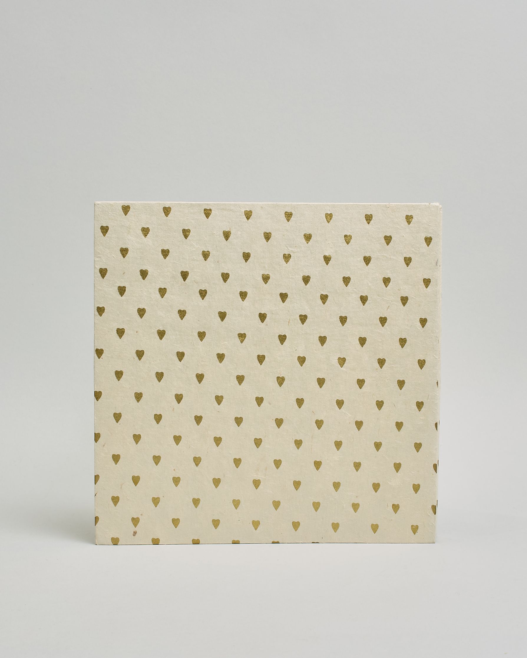 Ein Quadratisches Fotoalbum oder Gästebuch mit Hardcover in naturweißer Grundfarbe und darauf goldene kleine Herzen, die über das ganze Cover verteilt sind. In der Mitte befindet sich ein rechteckeiges Fenster hinter dem man ein Einlageblatt mit kalligrafiertem Text befestigen kann. #3