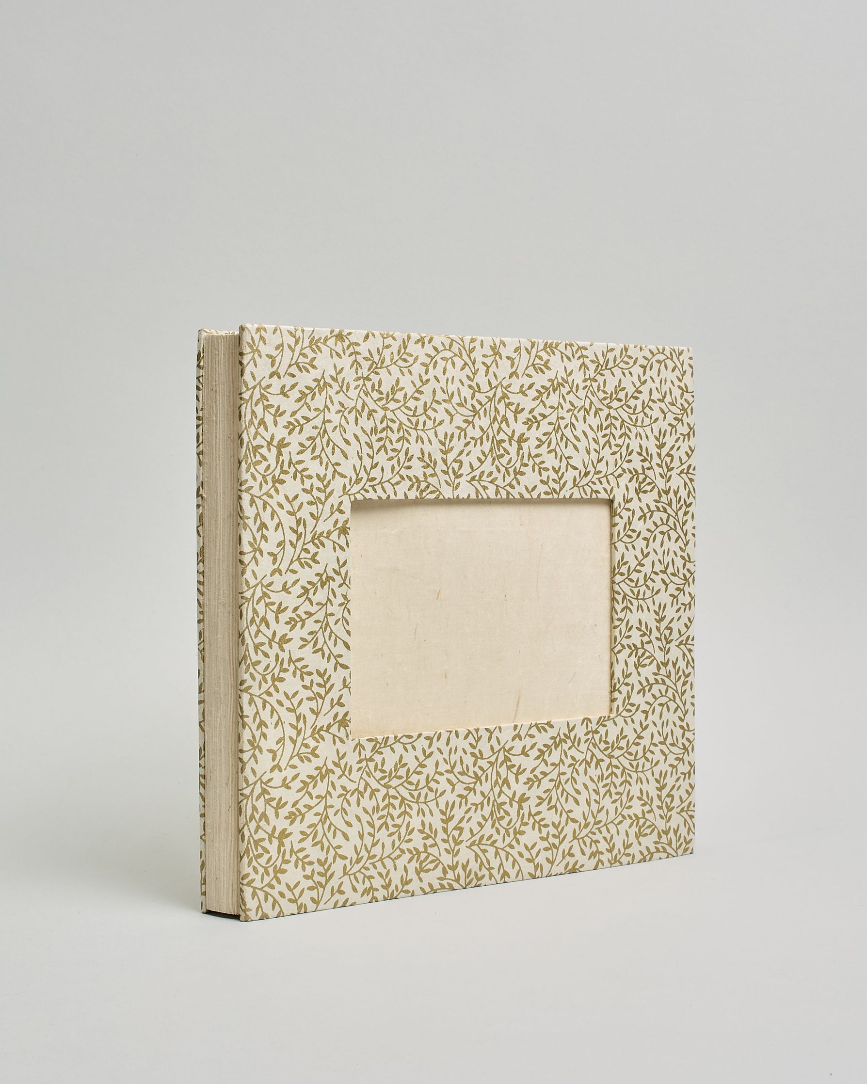 Ein Quadratisches Fotoalbum oder Gästebuch mit Hardcover in naturweißer Grundfarbe und darauf goldene Zweigen mit Blättern daran, die über das ganze Cover verteilt sind. In der Mitte befindet sich ein rechteckeiges Fenster hinter dem man ein Einlageblatt mit kalligrafiertem Text befestigen kann. #1