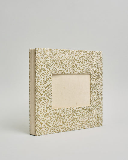 Ein Quadratisches Fotoalbum oder Gästebuch mit Hardcover in naturweißer Grundfarbe und darauf goldene Zweigen mit Blättern daran, die über das ganze Cover verteilt sind. In der Mitte befindet sich ein rechteckeiges Fenster hinter dem man ein Einlageblatt mit kalligrafiertem Text befestigen kann. #1