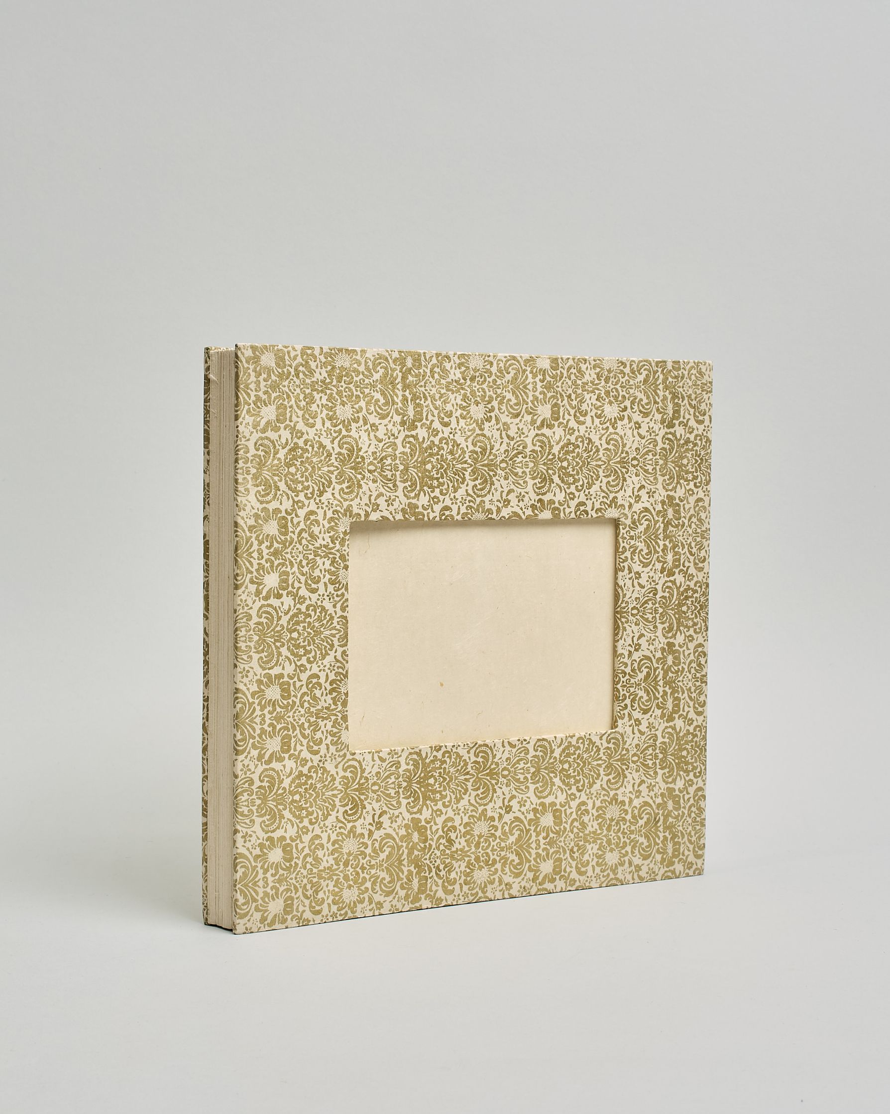 Ein Quadratisches Fotoalbum oder Gästebuch mit Hardcover in naturweißer Grundfarbe und darauf ein prunkvolles goldenes Barockmuster, das sich über das ganze Cover verteilt. In der Mitte befindet sich ein rechteckeiges Fenster hinter dem man ein Einlageblatt mit kalligrafiertem Text befestigen kann. #1