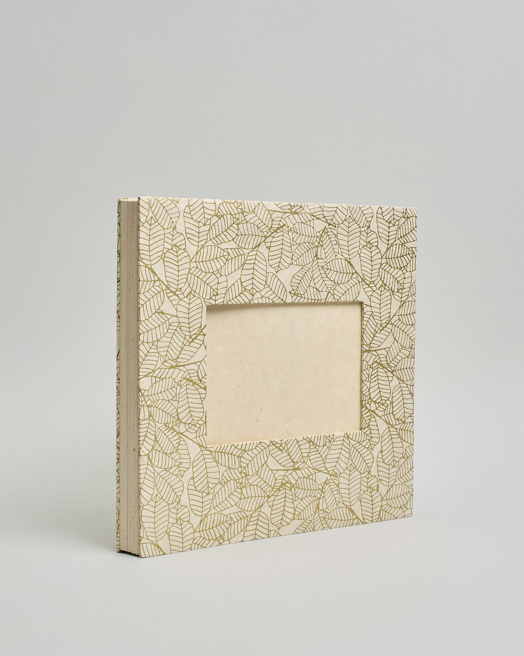 Ein Quadratisches Fotoalbum oder Gästebuch mit Hardcover in naturweißer Grundfarbe und darauf goldene Blätter, die über das ganze Cover verteilt sind. In der Mitte befindet sich ein rechteckeiges Fenster hinter dem man ein Einlageblatt mit kalligrafiertem Text befestigen kann. #1