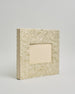 Ein Quadratisches Fotoalbum oder Gästebuch mit Hardcover in naturweißer Grundfarbe und darauf goldene Blätter, die über das ganze Cover verteilt sind. In der Mitte befindet sich ein rechteckeiges Fenster hinter dem man ein Einlageblatt mit kalligrafiertem Text befestigen kann. #1