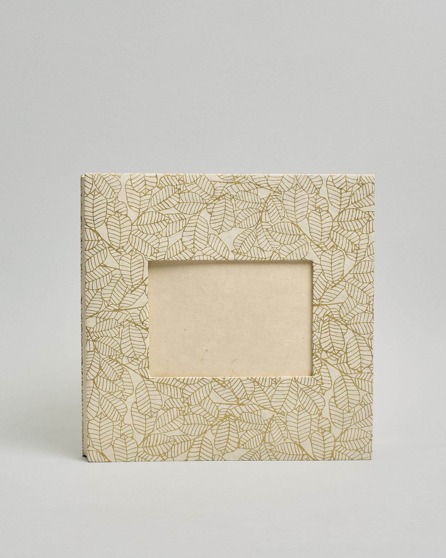 Ein Quadratisches Fotoalbum oder Gästebuch mit Hardcover in naturweißer Grundfarbe und darauf goldene Blätter, die über das ganze Cover verteilt sind. In der Mitte befindet sich ein rechteckeiges Fenster hinter dem man ein Einlageblatt mit kalligrafiertem Text befestigen kann. #2