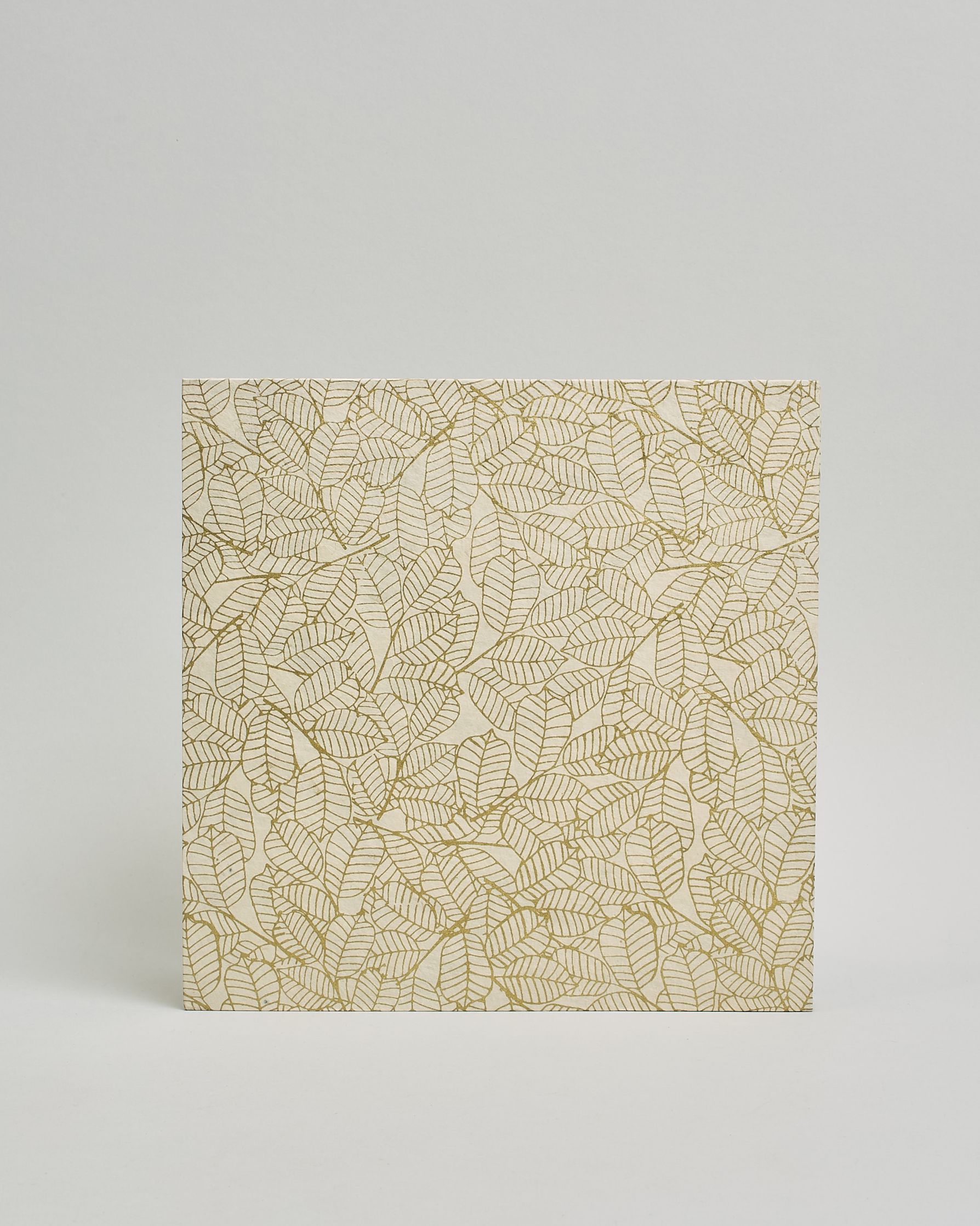 Ein Quadratisches Fotoalbum oder Gästebuch mit Hardcover in naturweißer Grundfarbe und darauf goldene Blätter, die über das ganze Cover verteilt sind. In der Mitte befindet sich ein rechteckeiges Fenster hinter dem man ein Einlageblatt mit kalligrafiertem Text befestigen kann. #3