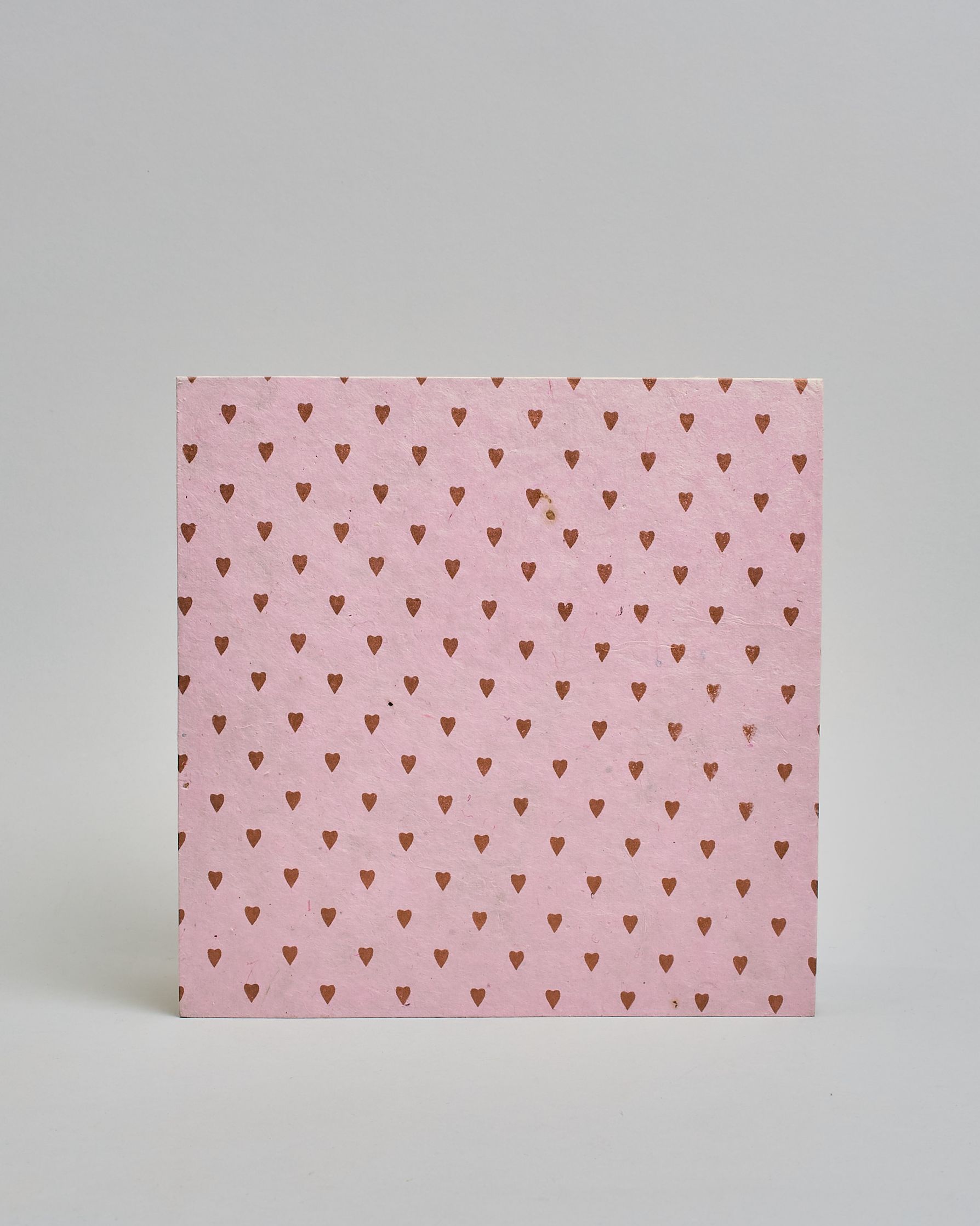 Ein Quadratisches Fotoalbum oder Gästebuch mit Hardcover in rosaner Grundfarbe und darauf roséfarbene kleinen Herzen, die über das ganze Cover verteilt sind. In der Mitte befindet sich ein rechteckeiges Fenster hinter dem man ein Einlageblatt mit kalligrafiertem Text befestigen kann. #3