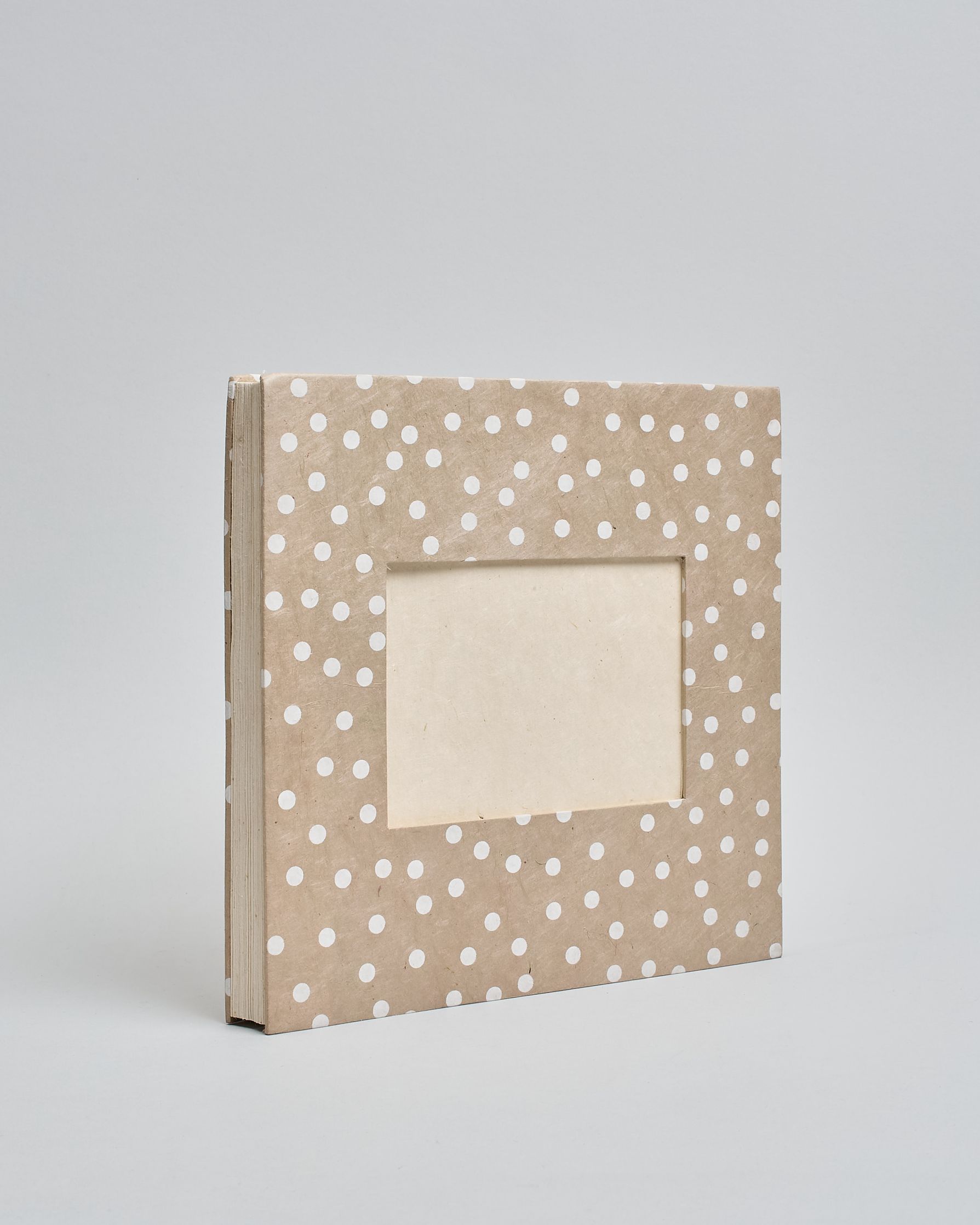 Ein Quadratisches Fotoalbum oder Gästebuch mit Hardcover in beiger Grundfarbe und darauf weiße Punkte, die über das ganze Cover verteilt sind. In der Mitte befindet sich ein rechteckeiges Fenster hinter dem man ein Einlageblatt mit kalligrafiertem Text befestigen kann. #1