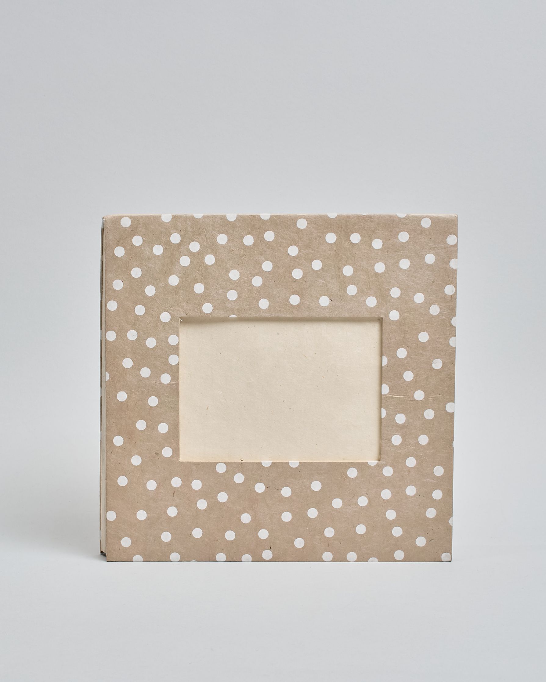 Ein Quadratisches Fotoalbum oder Gästebuch mit Hardcover in beiger Grundfarbe und darauf weiße Punkte, die über das ganze Cover verteilt sind. In der Mitte befindet sich ein rechteckeiges Fenster hinter dem man ein Einlageblatt mit kalligrafiertem Text befestigen kann. #2
