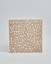 Ein Quadratisches Fotoalbum oder Gästebuch mit Hardcover in beiger Grundfarbe und darauf weiße Punkte, die über das ganze Cover verteilt sind. In der Mitte befindet sich ein rechteckeiges Fenster hinter dem man ein Einlageblatt mit kalligrafiertem Text befestigen kann. #3