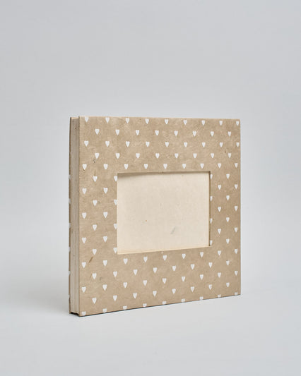 Ein Quadratisches Fotoalbum oder Gästebuch mit Hardcover in beiger Grundfarbe und darauf weiße Herzen, die über das ganze Cover verteilt sind. In der Mitte befindet sich ein rechteckeiges Fenster hinter dem man ein Einlageblatt mit kalligrafiertem Text befestigen kann. #1