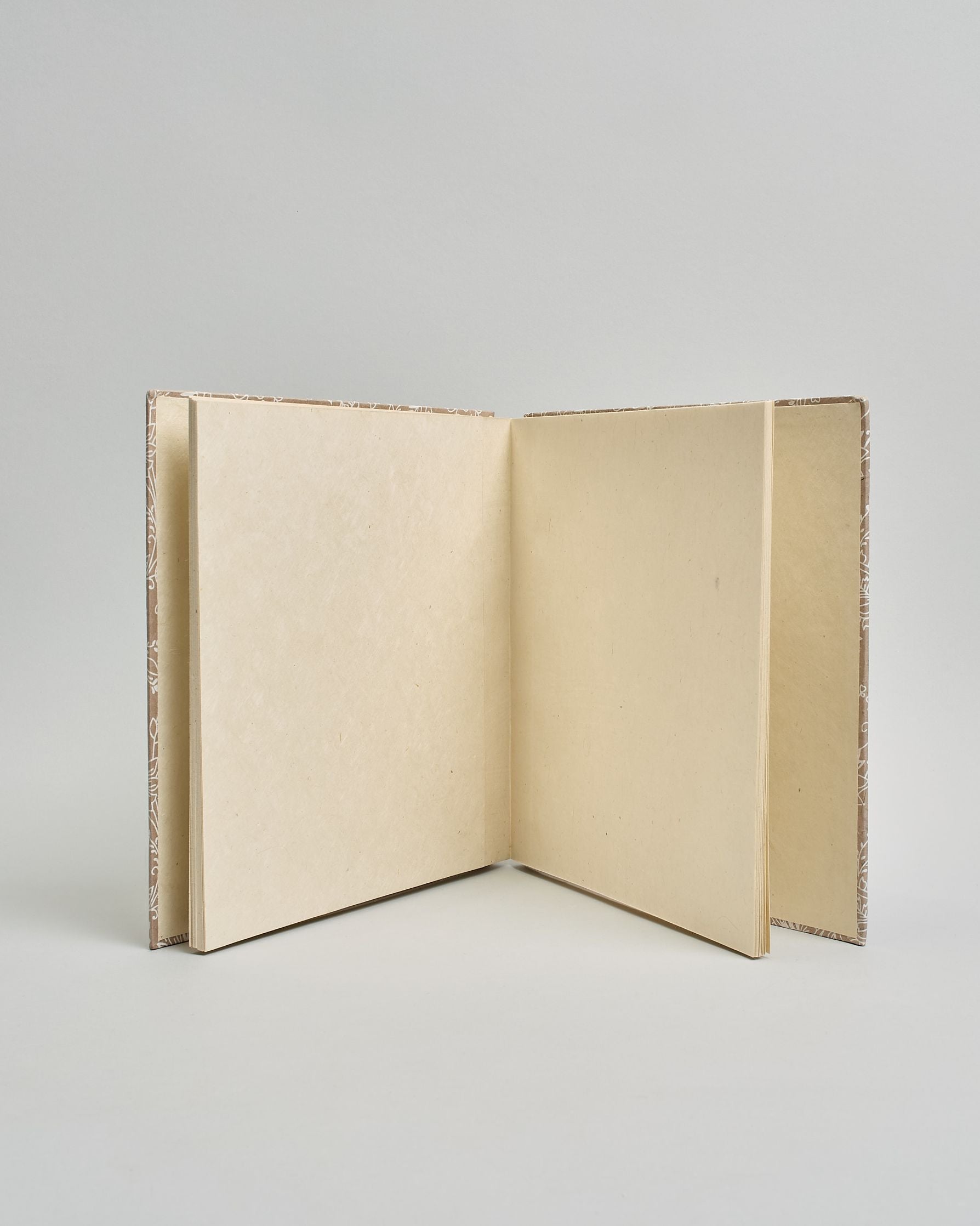 Ein Quadratisches Fotoalbum oder Gästebuch mit Hardcover in beiger Grundfarbe und darauf weiße Blumen, die über das ganze Cover verteilt sind. In der Mitte befindet sich ein rechteckeiges Fenster hinter dem man ein Einlageblatt mit kalligrafiertem Text befestigen kann. #3