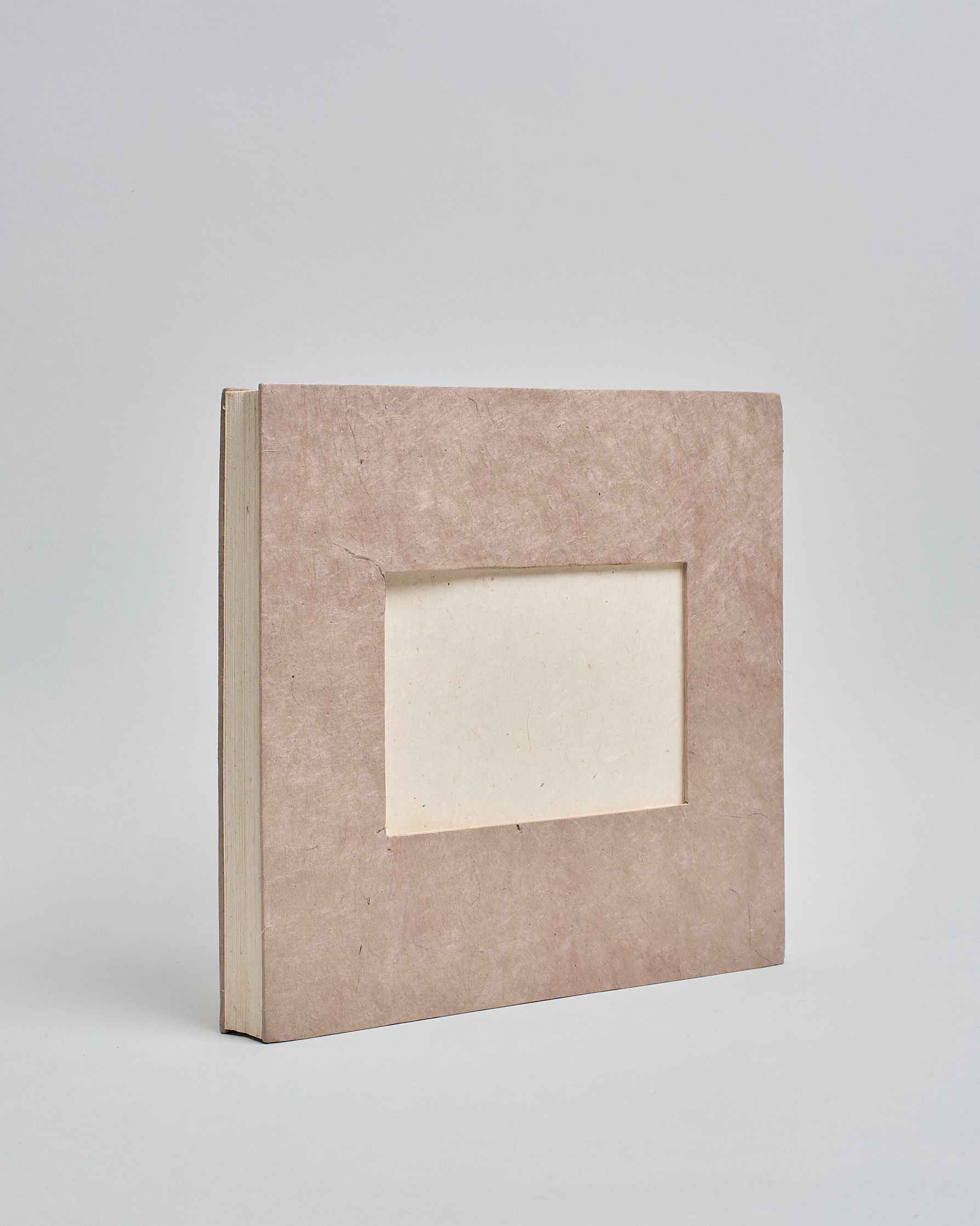 Ein Quadratisches Fotoalbum oder Gästebuch mit Hardcover in naturfarbener, weißer Grundfarbe, in der Mitte befindet sich ein rechteckeiges Fenster hinter dem man ein Einlageblatt mit kalligrafiertem Text befestigen kann. #1