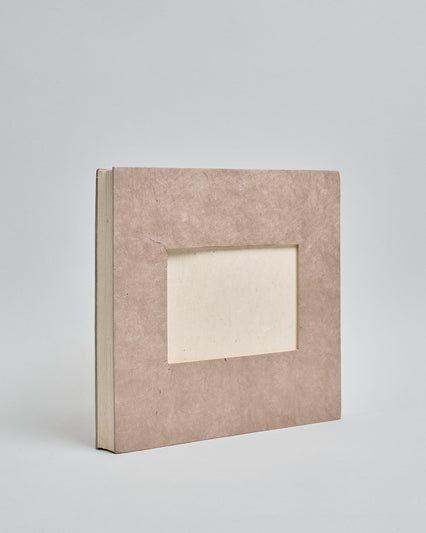 Ein Quadratisches Fotoalbum oder Gästebuch mit Hardcover in naturfarbener, weißer Grundfarbe, in der Mitte befindet sich ein rechteckeiges Fenster hinter dem man ein Einlageblatt mit kalligrafiertem Text befestigen kann. #1