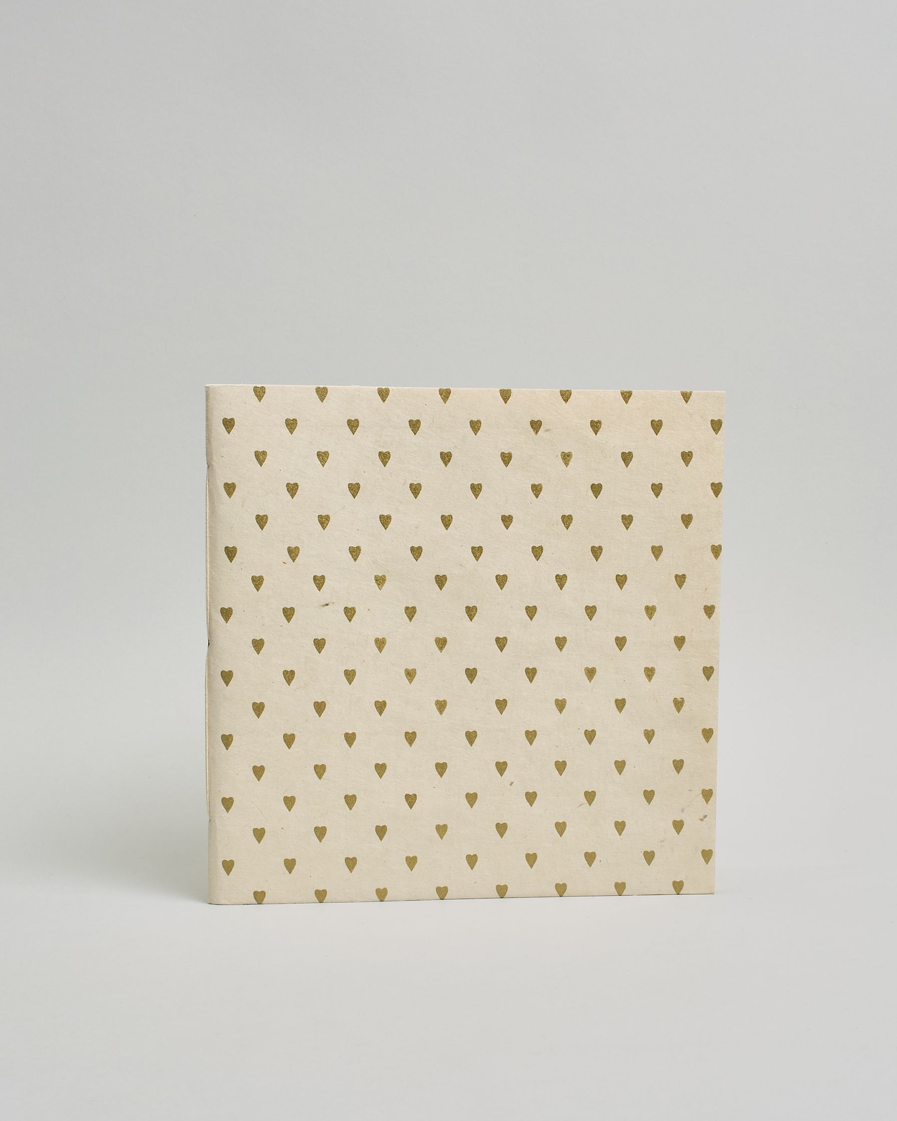 Ein Quadratisches Fotoalbum oder Gästebuch mit Softcover in naturweißer Grundfarbe und darauf goldene kleine Herzen, die über das ganze Cover verteilt sind. #2