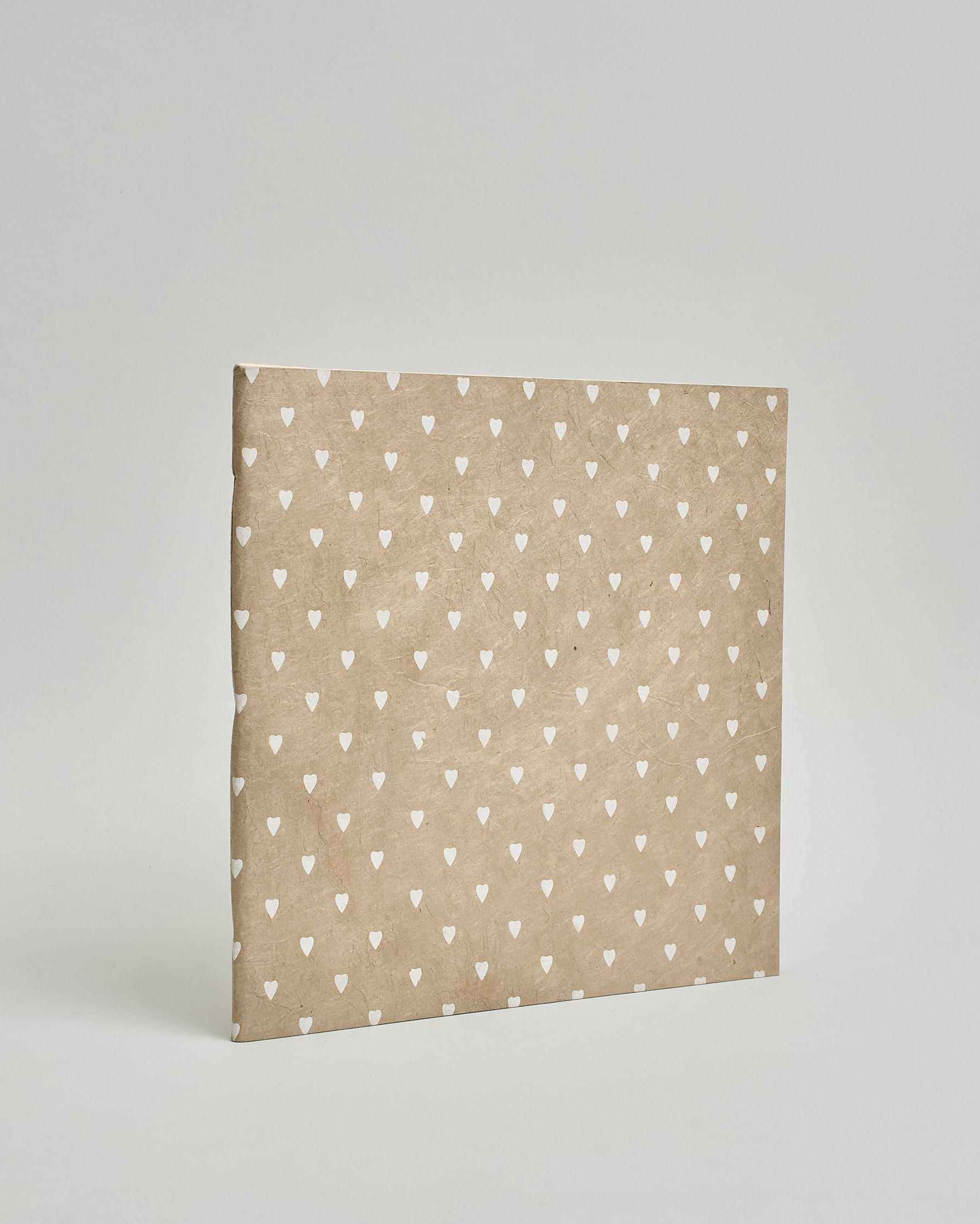 Ein Quadratisches Fotoalbum oder Gästebuch mit Softcover in beiger Grundfarbe und darauf weiße kleine Herzen, die über das ganze Cover verteilt sind. #1