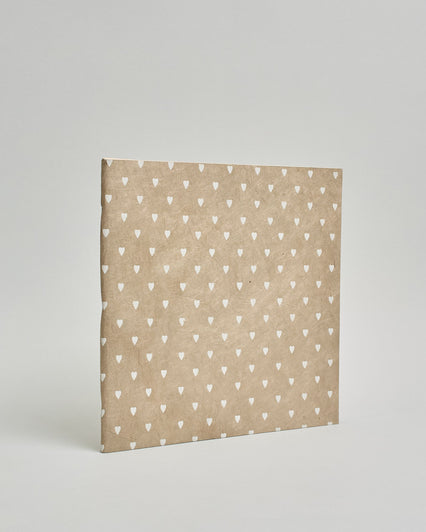 Ein Quadratisches Fotoalbum oder Gästebuch mit Softcover in beiger Grundfarbe und darauf weiße kleine Herzen, die über das ganze Cover verteilt sind. #1