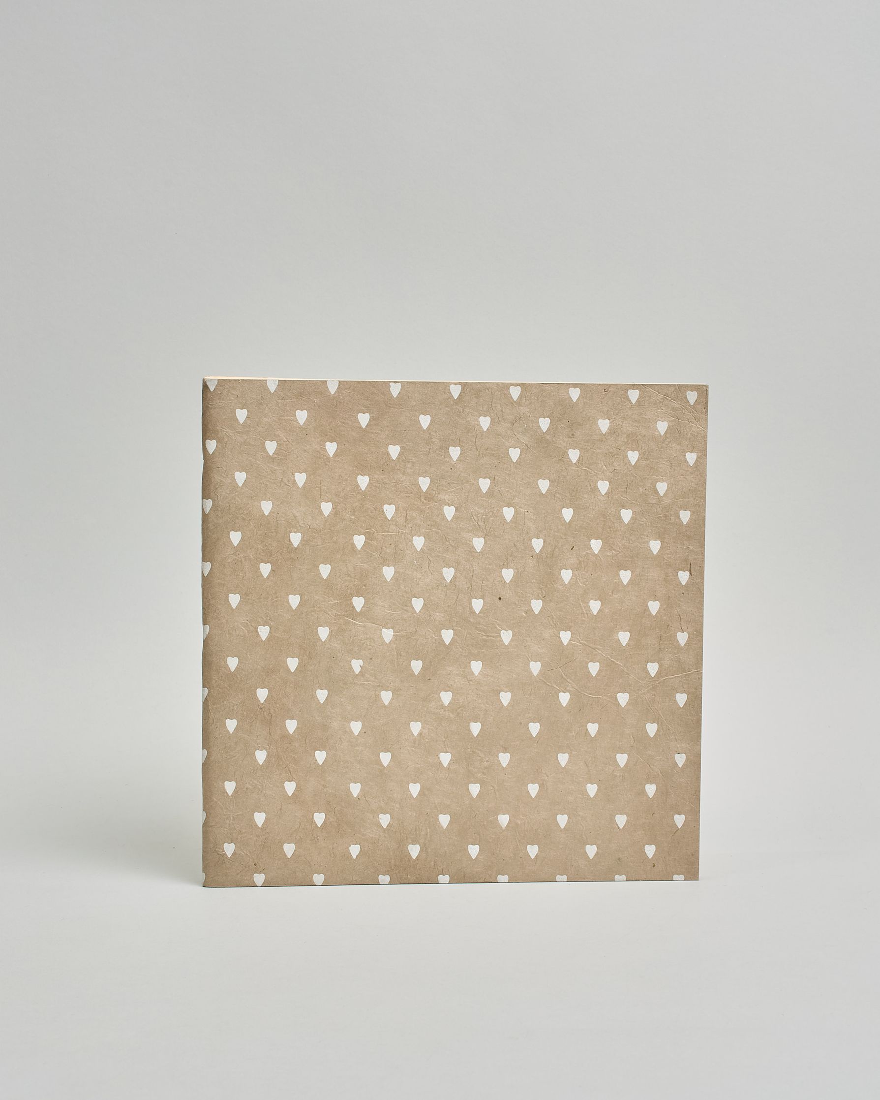 Ein Quadratisches Fotoalbum oder Gästebuch mit Softcover in beiger Grundfarbe und darauf weiße kleine Herzen, die über das ganze Cover verteilt sind. #2