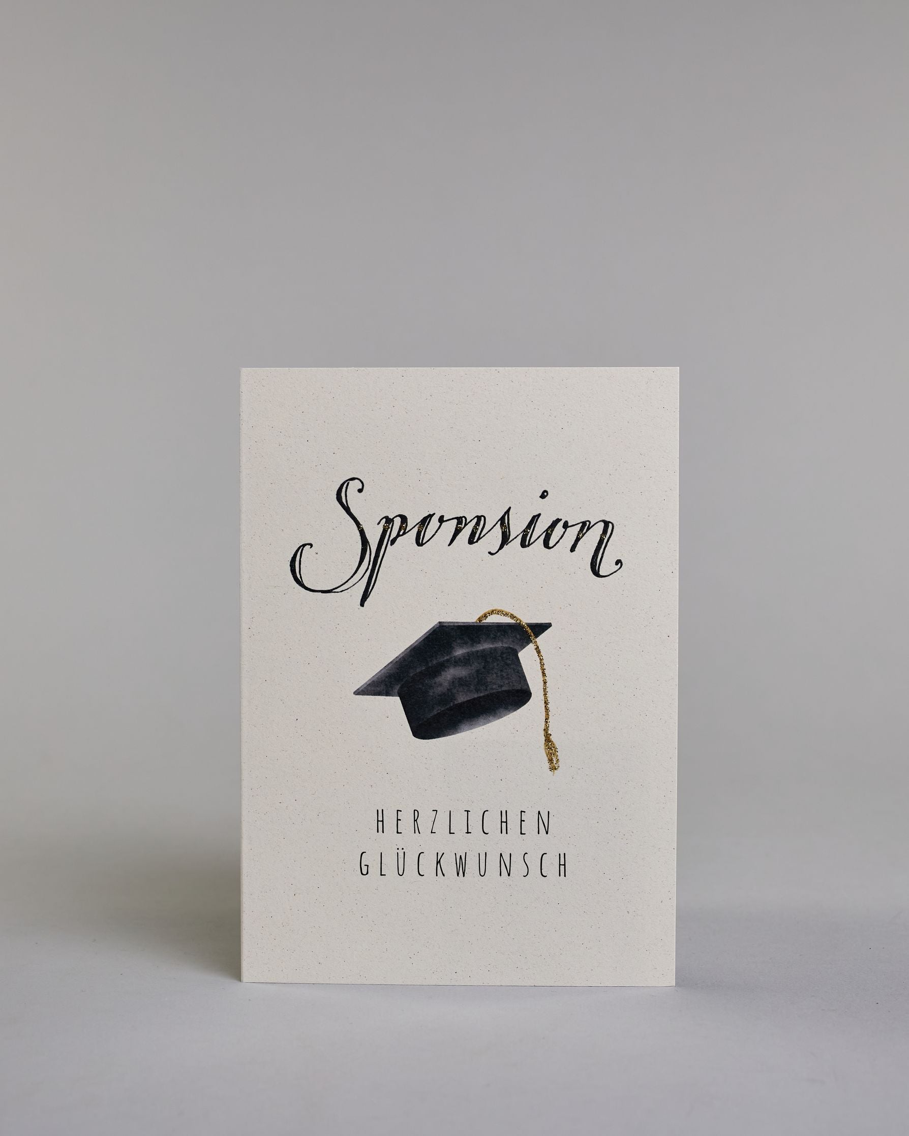 Glückwunschkarte zur Sponsion mit schwarzer Kalligrafieaufschrift ‚Sponsion‘, darunter ein schwarzer Doktorhut mit goldener Quaste und der Text ‚Herzlichen Glückwunsch‘ auf hellem Hintergrund. Dazu ein grün-goldenes handgeschöpftes Kuvert. #1