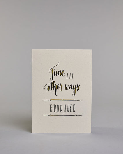 Glückwunschkarte zum Abschied nehmen, auf Englisch mit dem Text ‚time for other ways good luck‘. Mit schwarzer Kalligrafieaufschrift ‚time for‘, darunter ‚other ways‘, darunter zwischen zwei horizontalen Linien ‚GOOD LUCK‘ in dünner Kalligrafieaufschrift auf hellem Hintergrund. Dazu ein grün-goldenes Kuvert. #1