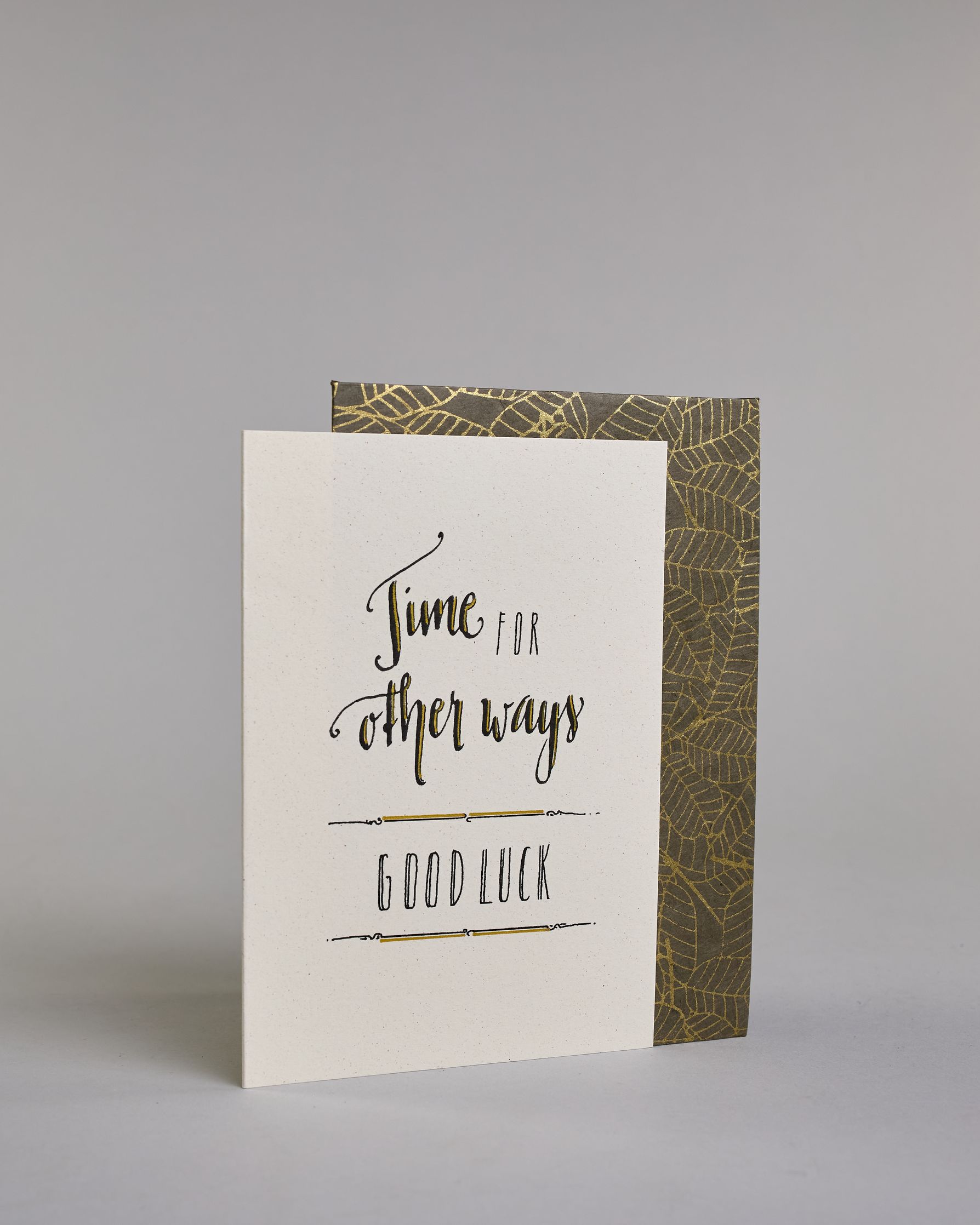 Glückwunschkarte zum Abschied nehmen, auf Englisch mit dem Text ‚time for other ways good luck‘. Mit schwarzer Kalligrafieaufschrift ‚time for‘, darunter ‚other ways‘, darunter zwischen zwei horizontalen Linien ‚GOOD LUCK‘ in dünner Kalligrafieaufschrift auf hellem Hintergrund. Dazu ein grün-goldenes Kuvert. #3