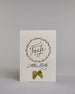 Glückwunschkarte zur Taufe mit geschwungener schwarzer Kalligrafieaufschrift in gezeichnetem Kranz ‚Taufe‘, darunter der Text ‚Alles Liebe‘, darunter eine aufgenähte goldene Masche auf hellem Hintergrund. Dazu ein weiß-goldenes handgeschöpftes Kuvert. #1