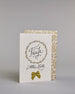 Glückwunschkarte zur Taufe mit geschwungener schwarzer Kalligrafieaufschrift in gezeichnetem Kranz ‚Taufe‘, darunter der Text ‚Alles Liebe‘, darunter eine aufgenähte goldene Masche auf hellem Hintergrund. Dazu ein weiß-goldenes handgeschöpftes Kuvert. #3
