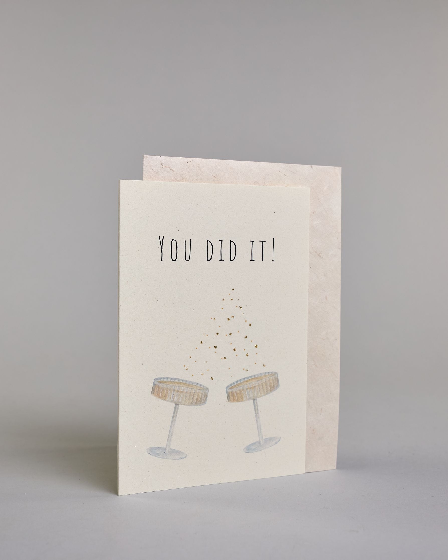 Glückwunschkarte zu einem allgemeinen Erfolg oder zu einer Hochzeit in Englisch mit schwarzer Kalligrafieaufschrift  ‚You did it!‘,  darunter zwei gezeichnete Champagnergläser die anstoßen, zwischen dem Text und den Gläsern sind vergoldete Pünktchen auf hellem Hintergrund. Dazu ein weißes handgeschöpftes Kuvert. #3