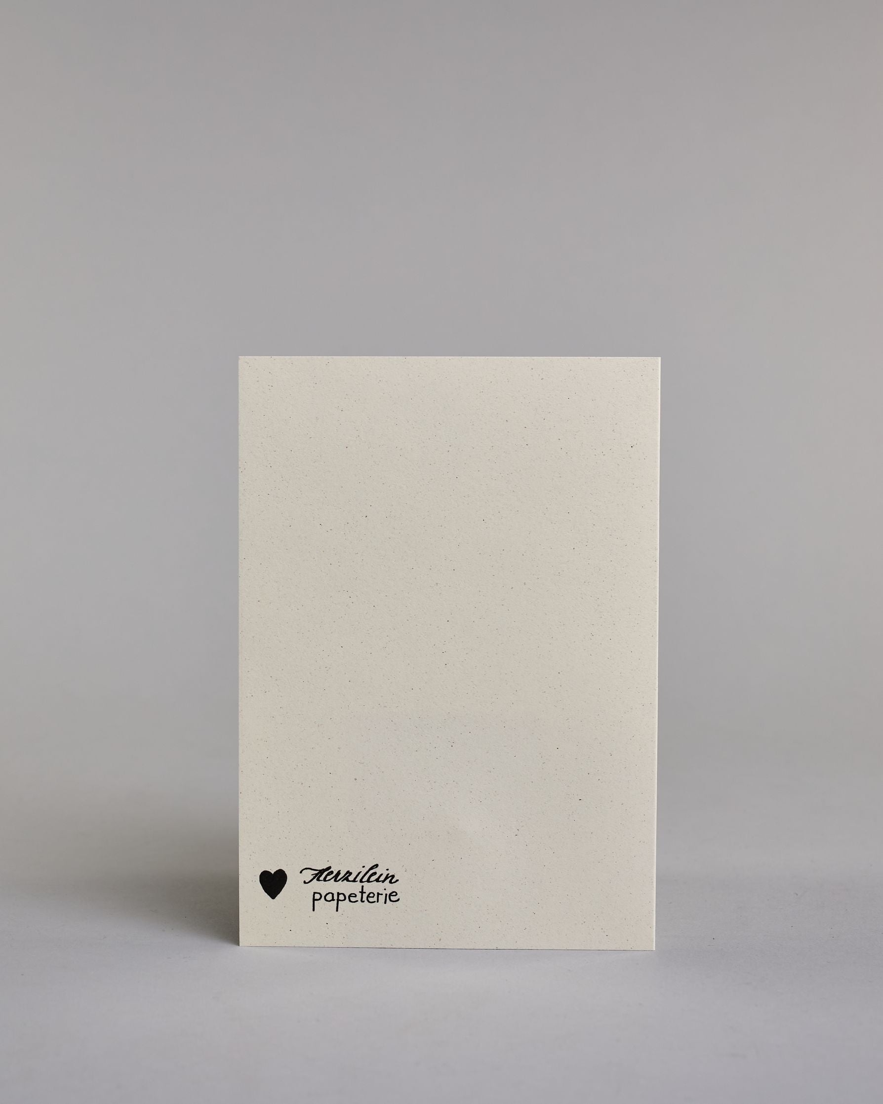 Glückwunschkarte zur Geburt mit schwarzer Kalligrafieaufschrift ‚Willkommen kleiner Engel‘, ‚Willkommen‘ steht in geschwungener Kalligrafieaufschrift über einem gezeichnetem Kranz, untem auf dem Kranz ist eine goldene Masche aufgenäht. Der Text im Kranz setzt sich auf folgenden Zeilen zusammen:  ‚KLEINER‘ in dünner gerader Kalligrafieaufschrift, darunter ‚Engel‘, auf hellem Hintergrund. Dazu ein gold-weißes handgeschöpftes Kuvert. #4