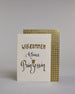 Glückwunschkarte zur Geburt mit schwarzer Kalligrafieaufschrift ‚Willkommen kleine Prinzessin‘, der Text setzt sich auf folgenden Zeilen zusammen:  ‚WILLKOMMEN‘ in gold gefüllten Kalligrafiebuchstaben, darunter‚kleine‘ in geschwungener schwarzer Kalligrafieaufschrift, darunter ‚Prinzessin‘ in verglitzerter Kalligrafieaufschrift, über dem ‚z‘ ist eine gezeichnete goldene Krone auf hellem Hintergrund. Dazu ein gold-weißes handgeschöpftes Kuvert. #2