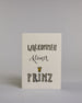 Glückwunschkarte zur Geburt mit der Aufschrift „Willkommen kleiner Prinz“ in schwarzer Kalligrafieaufschrift, wobei das Wort „Willkommen" und „Prinz“ mit goldfarbenen Details verziert ist. Über dem Wort „Prinz“ ist eine kleine goldene Krone abgebildet. Dazu ein grün-goldenes handgeschöpftes Kuvert. #1