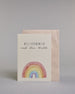 Glückwunschkarte zur Geburt mit der Aufschrift „Willkommen auf der Welt“ in schwarzer Handlettering-Schrift. Darunter ist ein bunter Regenbogen in Aquarelloptik mit den Farben Rot, Orange, Gelb, Grün, Blau und Lila abgebildet. Dazu ein beige-weißes handgeschöpftes Kuvert. #2