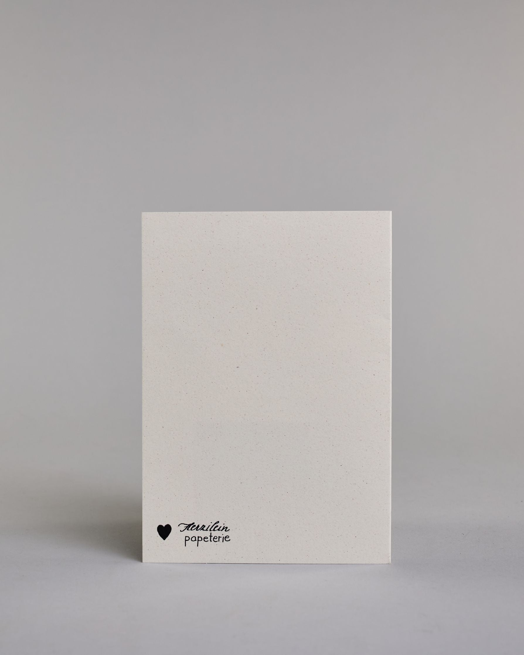 Glückwunschkarte zur Geburt mit der Aufschrift „Willkommen kleines Wunder“ in schwarzer Handlettering-Schrift. Das "willkommen kleines" ist in geschwungener Kalligrafieaufschrift, darunter das "WUNDER" in gerader Schrift dargestellt. Darunter verläuft schräg über die Karte ein Schwarm goldfarbener Sterne in verschiedenen Größen. Dazu ein gold-weißes handgeschöpftes Kuvert. #4