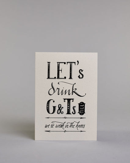 Karte in Englisch mit der Aufschrift „LET’s drink G&Ts till we’re weak in the knees“ in dekorativer schwarzer Handlettering-Schrift auf hellem Hintergrund. Die Zeilen setzten sich wiefolgt zusammen: "LET's" in gerader Schrift, darunter "drink" in geschwungener Schrift, darunte "G&Ts" in gerader Schrift, in der gleichen Zeile rechts daneben vertikal das "till" in einem Rahmen,  darunter "we're weak in the knees". Dazu ein grün-goldenes handgeschöpftes Kuvert. #1