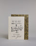 Karte mit der Aufschrift „Auf ins neue Abenteuer – Viel Glück, alles Gute“ in schwarzer Handlettering-Schrift. In der Mitte ist ein handgezeichnetes Schild in der Form eines Pfeiles der nach rechts weist, auf diesem befindet sich das Wort "Abenteuer", "AUF INS NEUE" steht darüber, "VIEL GLÜCK" und "alles Gute" darunter auf hellem Hintergrund. Dazu ein grün-goldenes handgeschöpftes Kuvert. #2