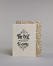 Karte in Englisch mit der Aufschrift „The best is yet to come“ in schwarzer Handlettering-Schrift, teilweise mit goldfarbenen Akzenten hervorgehoben. Über und unter dem Text sind kleine stilisierte, ebenfalls verglitzerte Feuerwerksmotive abgebildet. Dazu ein weiß-goldenes handgeschöpftes Kuvert. #2